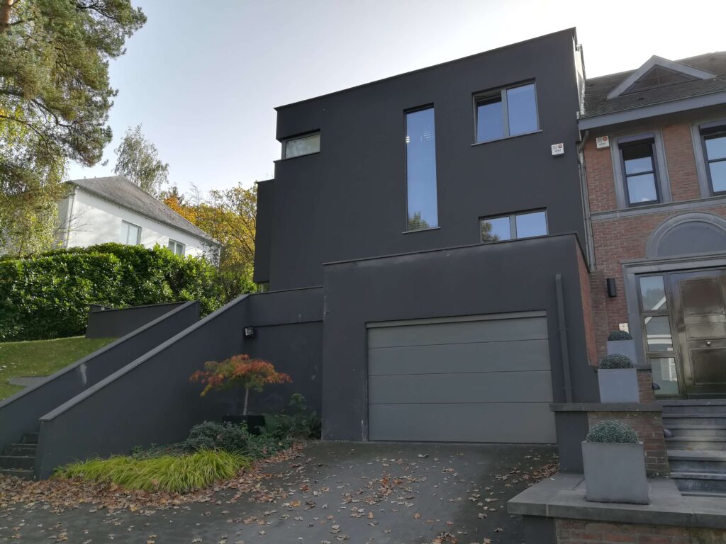 villa située à uccle avec escalier menant au 1er étage et porte de garage en pvc gris