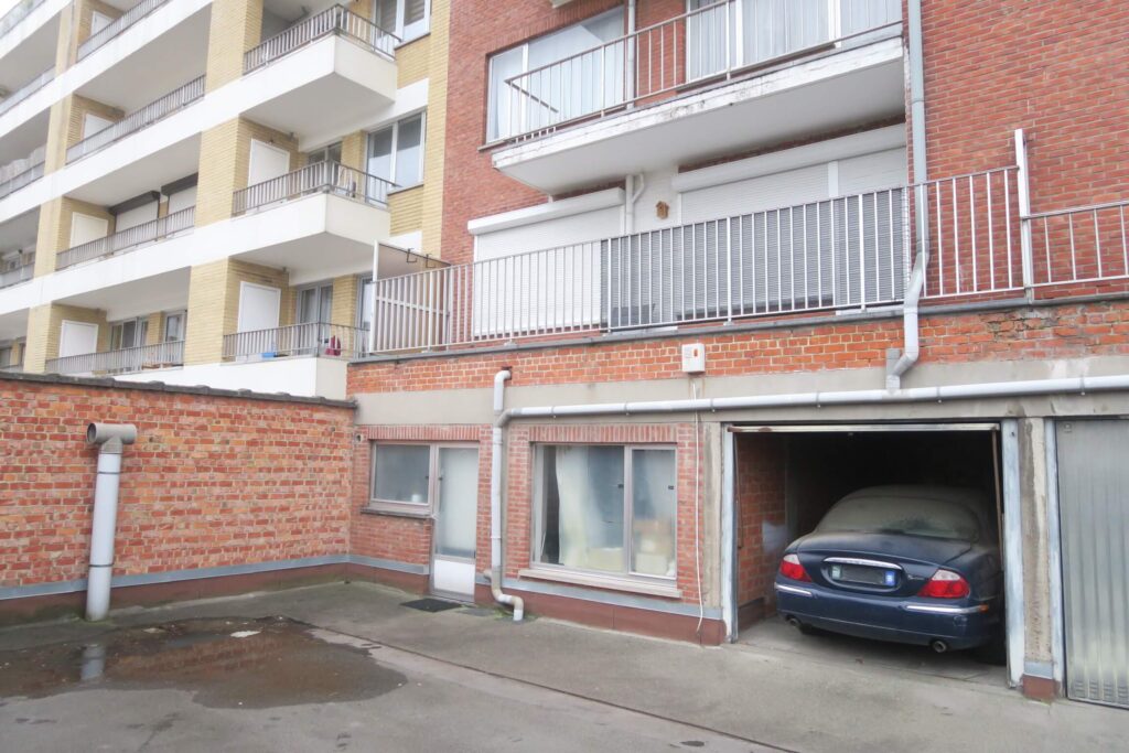 façade en briques rouge avec box de garages et cour en macadam