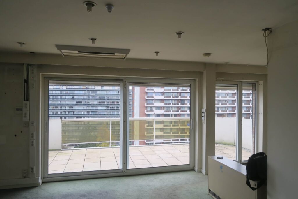 vue vers l’extérieur et la terrasse munie de garde-corps en verre depuis le séjour d’un penthouse