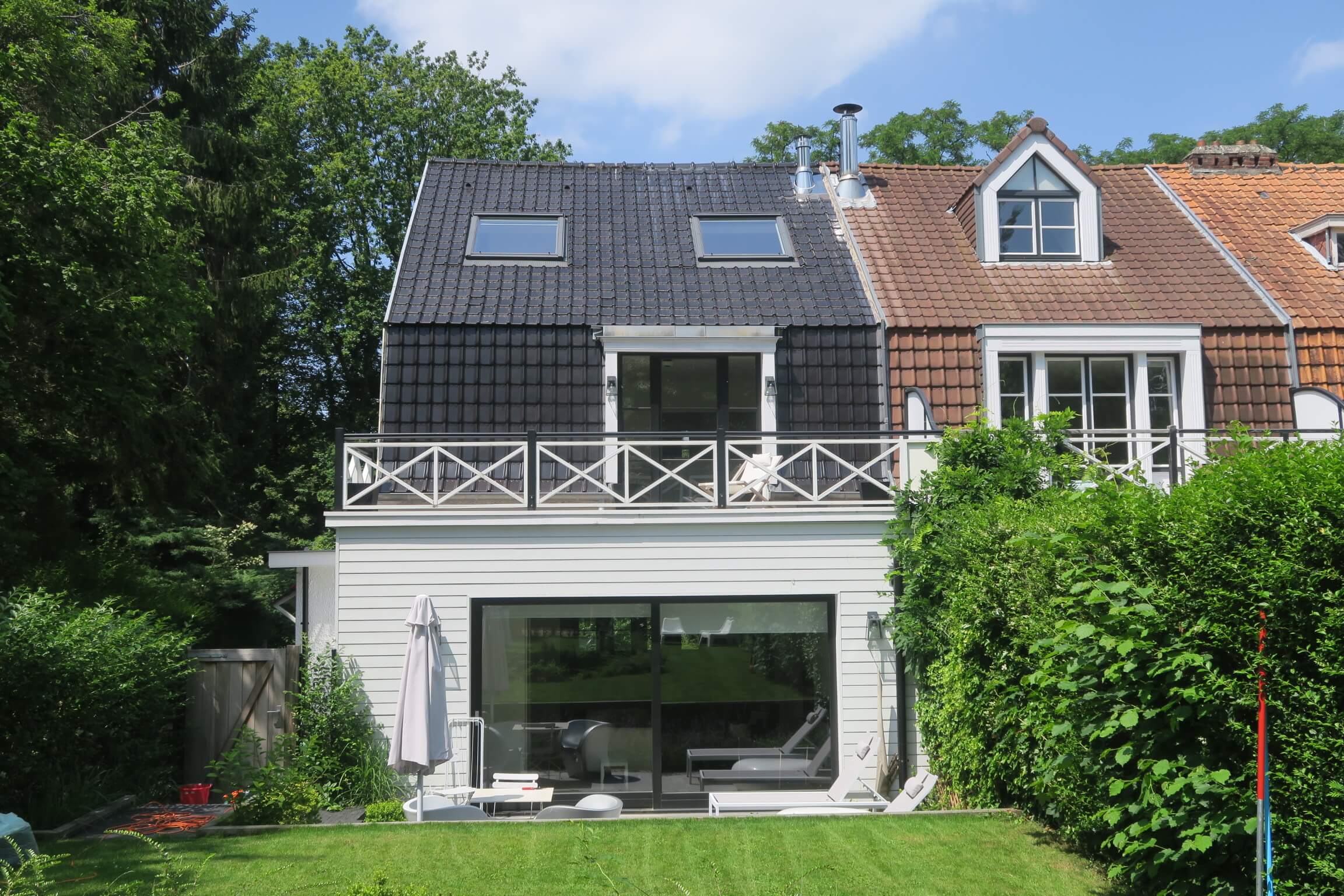 façade arrière d’une maison avec terrasse et garde-corps en bois