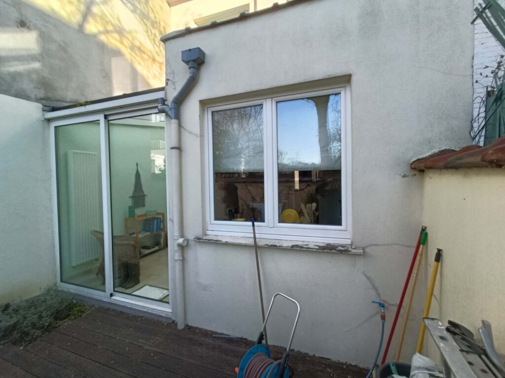 vue générale de la façade arrière de la maison avec son annexe véranda et présence d’une terrasse en bois